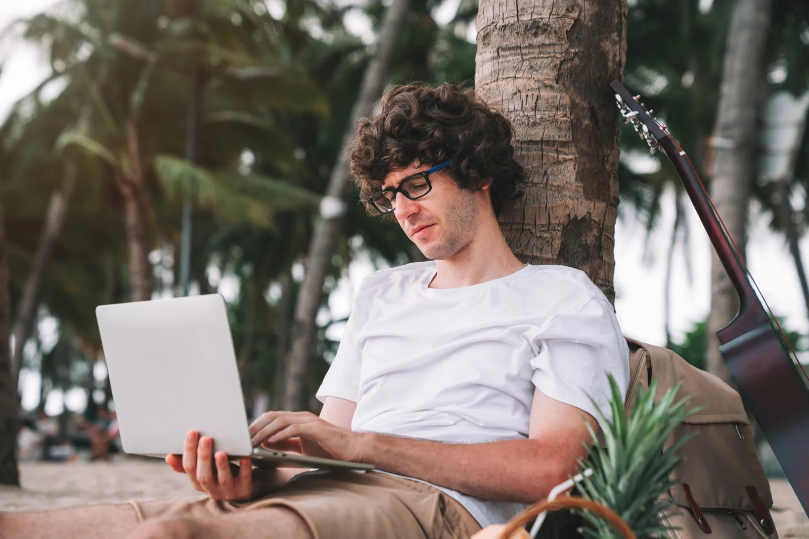 Mann nutzt einen Laptop am Strand – Studioverwaltung auch unterwegs über das Internet